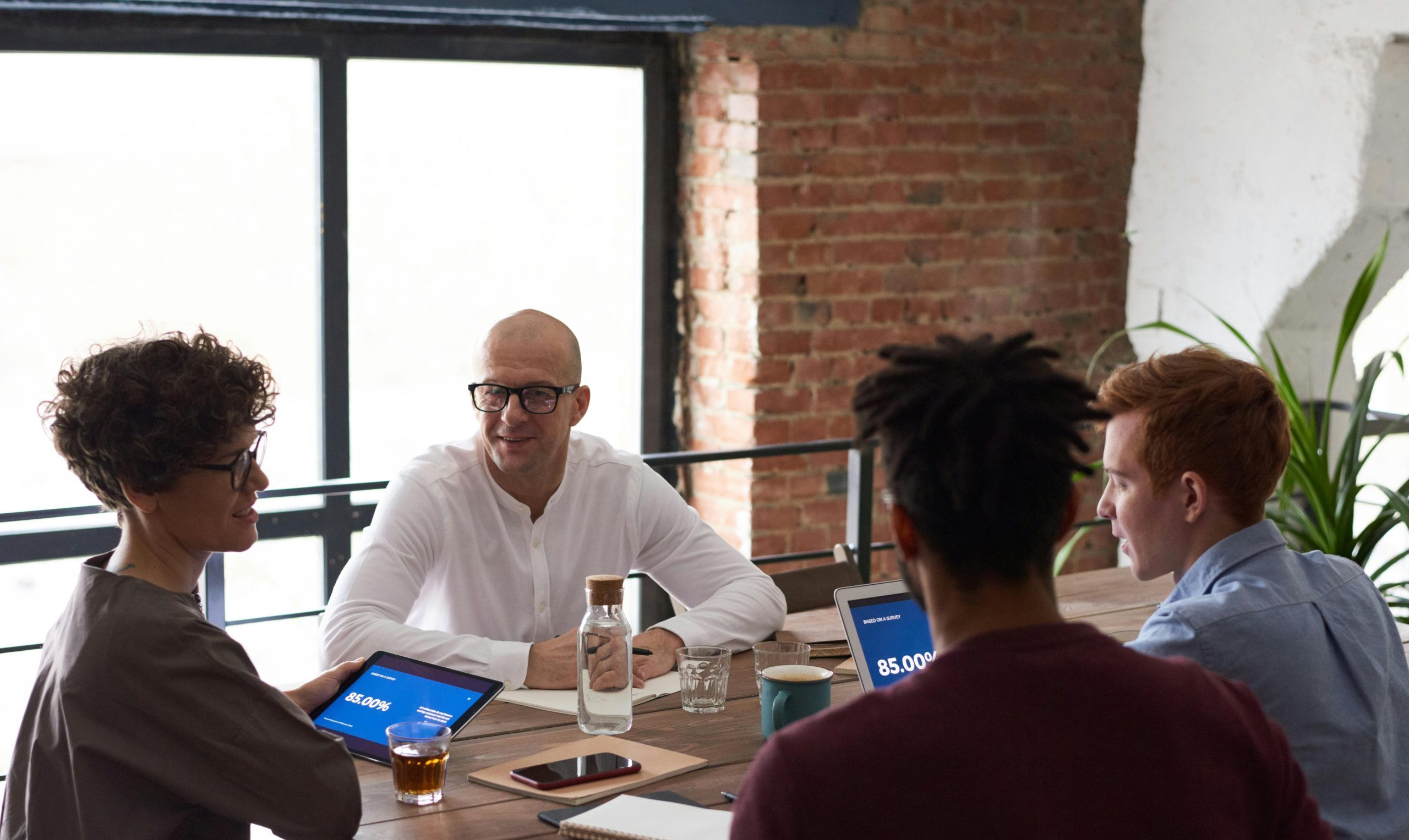 Diverse team collaborating in a modern office setting with laptops and notes on the table.